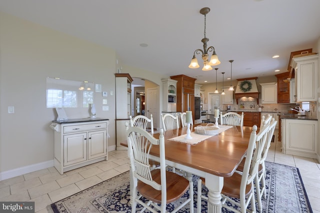 dining space with arched walkways, a notable chandelier, baseboards, and light tile patterned floors