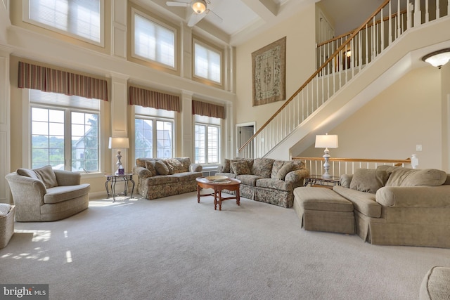 living area featuring carpet flooring, ceiling fan, a towering ceiling, and stairs