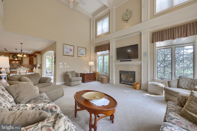 living area featuring light carpet, baseboards, arched walkways, and a glass covered fireplace