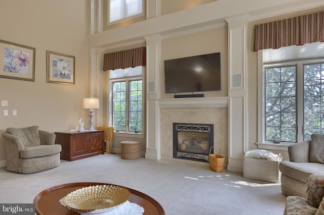 living area featuring a tile fireplace, carpet flooring, and a towering ceiling