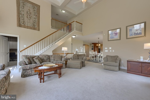 carpeted living room featuring a towering ceiling, ceiling fan, and stairs