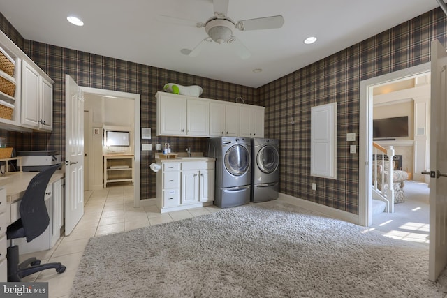 washroom with a sink, washing machine and clothes dryer, cabinet space, and wallpapered walls