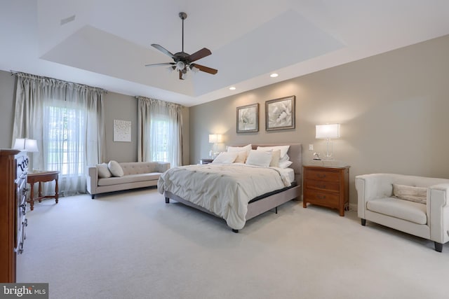 bedroom featuring recessed lighting, a raised ceiling, a ceiling fan, and light colored carpet