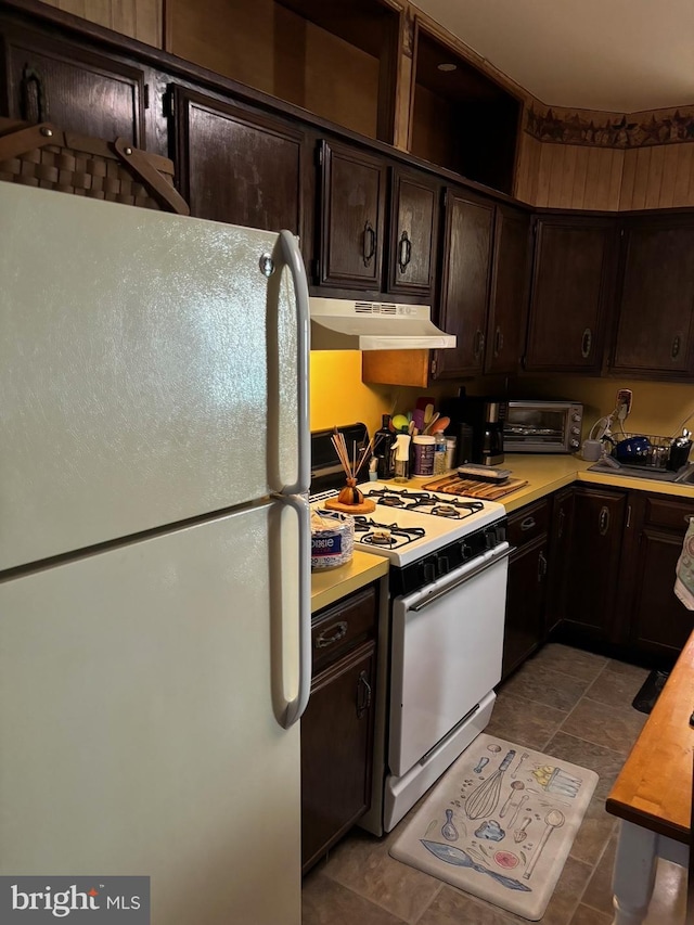 kitchen featuring dark brown cabinets, white appliances, and light tile patterned floors