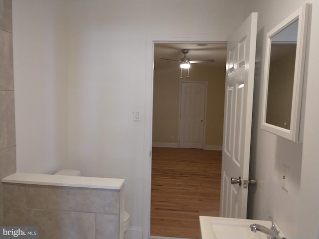 bathroom with wood-type flooring, ceiling fan, and toilet