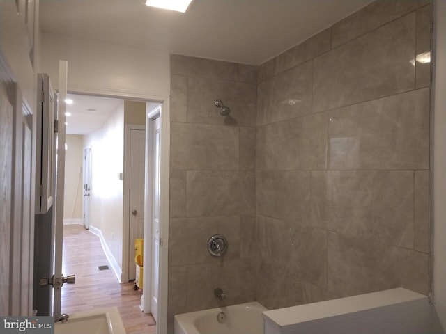 bathroom featuring hardwood / wood-style floors and tiled shower / bath combo