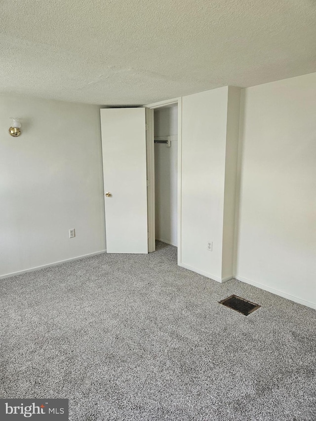 unfurnished bedroom with a textured ceiling, a closet, and carpet floors