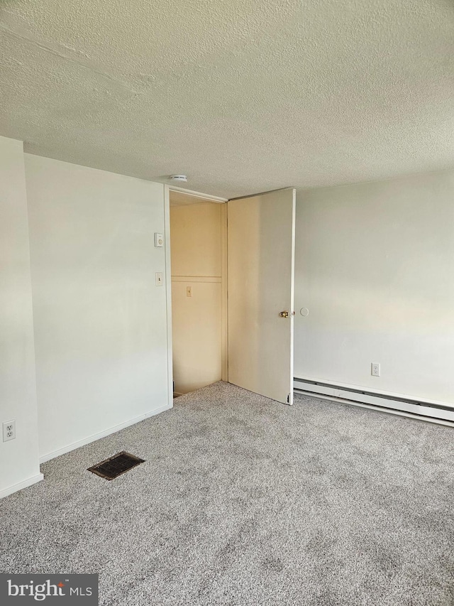 carpeted empty room with a baseboard heating unit and a textured ceiling