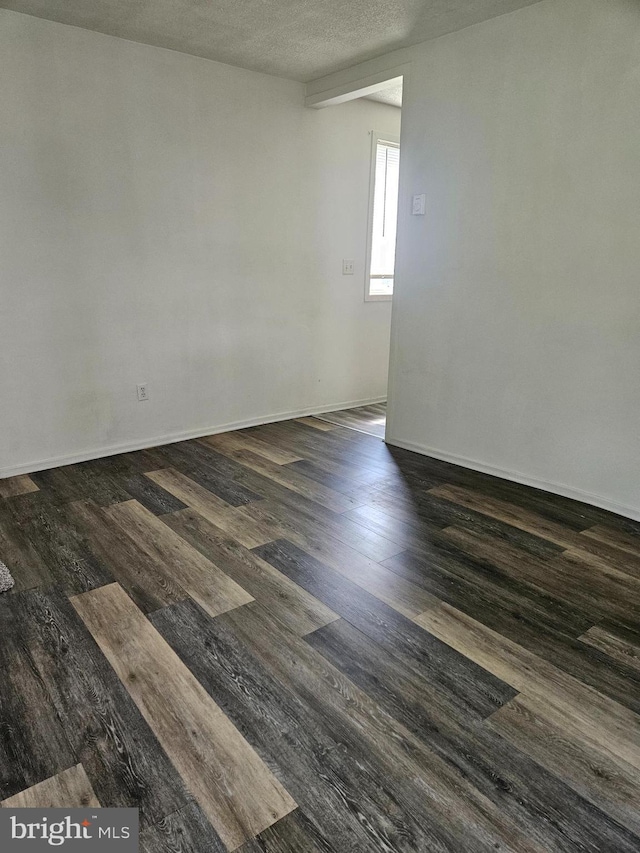 empty room with a textured ceiling and dark hardwood / wood-style flooring