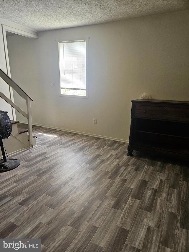 spare room featuring a textured ceiling and dark hardwood / wood-style flooring