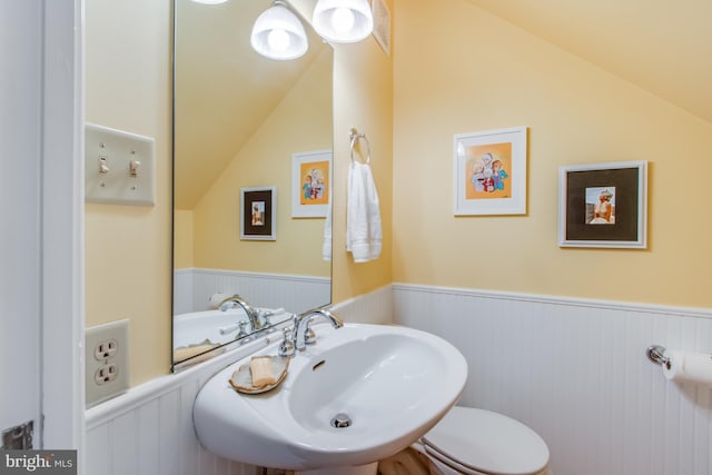 bathroom featuring toilet, vaulted ceiling, and sink