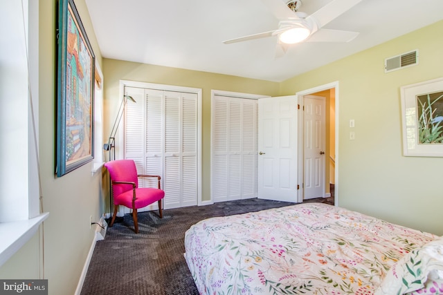 carpeted bedroom with ceiling fan and two closets