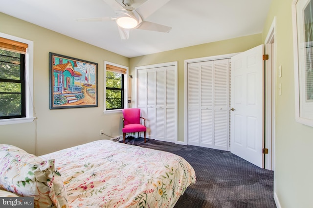 bedroom with ceiling fan, two closets, and dark carpet