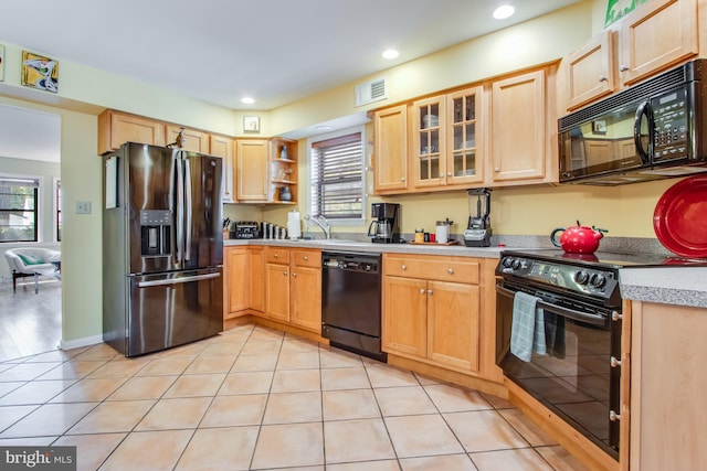 kitchen with light brown cabinetry, a wealth of natural light, light tile patterned floors, and black appliances