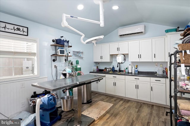 kitchen featuring white cabinets, sink, dark hardwood / wood-style floors, a wall unit AC, and vaulted ceiling