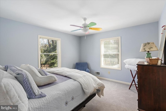 bedroom featuring ceiling fan, light colored carpet, and multiple windows