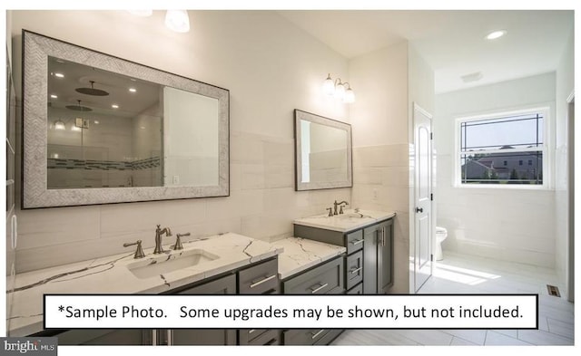 bathroom featuring vanity, toilet, tile walls, and walk in shower