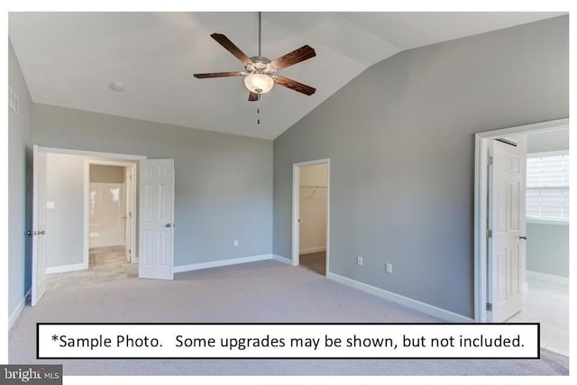 unfurnished bedroom featuring ceiling fan, light colored carpet, vaulted ceiling, a spacious closet, and a closet