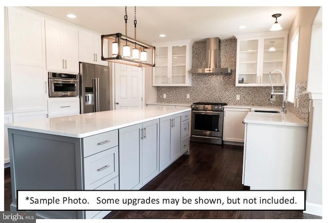 kitchen featuring pendant lighting, sink, white cabinetry, high end appliances, and wall chimney exhaust hood