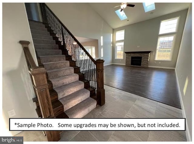 staircase with ceiling fan, a skylight, plenty of natural light, and high vaulted ceiling