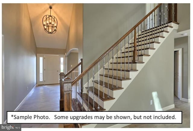 foyer entrance featuring wood-type flooring, a notable chandelier, and a high ceiling