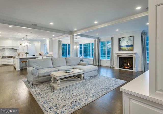 living room featuring a notable chandelier, dark hardwood / wood-style flooring, a premium fireplace, and crown molding