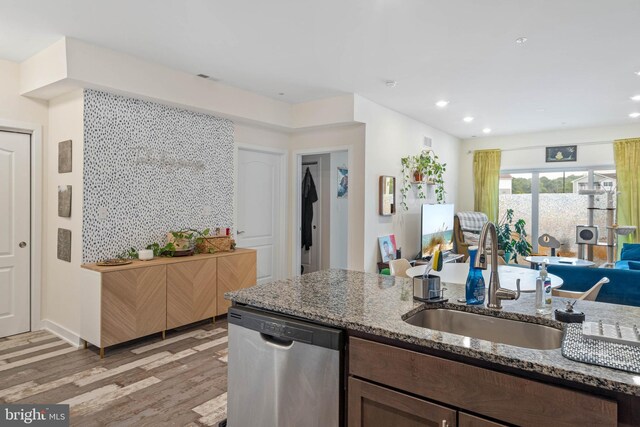 kitchen with dishwasher, sink, light stone counters, and light hardwood / wood-style floors