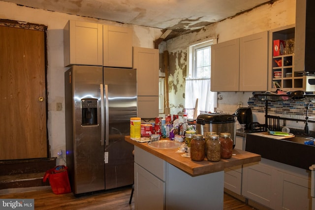 kitchen with gray cabinets, a kitchen island, sink, stainless steel fridge, and wood counters