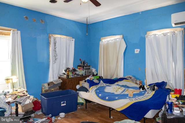 bedroom with ceiling fan, a wall mounted AC, and hardwood / wood-style flooring