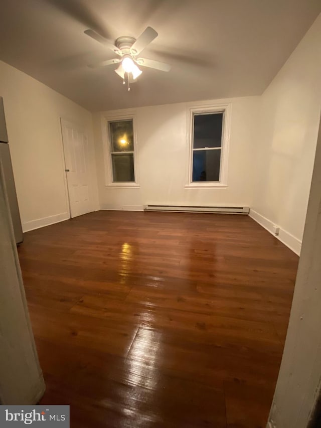 spare room with ceiling fan, dark hardwood / wood-style flooring, and a baseboard heating unit