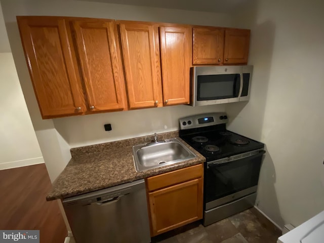 kitchen featuring dark stone countertops, sink, appliances with stainless steel finishes, and dark hardwood / wood-style flooring