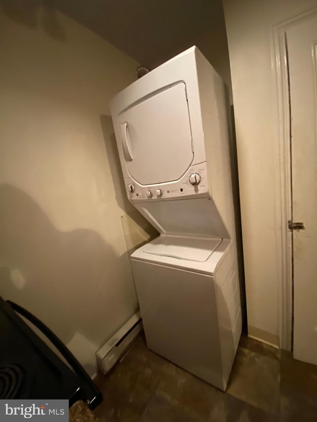 clothes washing area featuring a baseboard heating unit and stacked washer and dryer