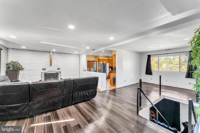 living room with a brick fireplace and hardwood / wood-style flooring