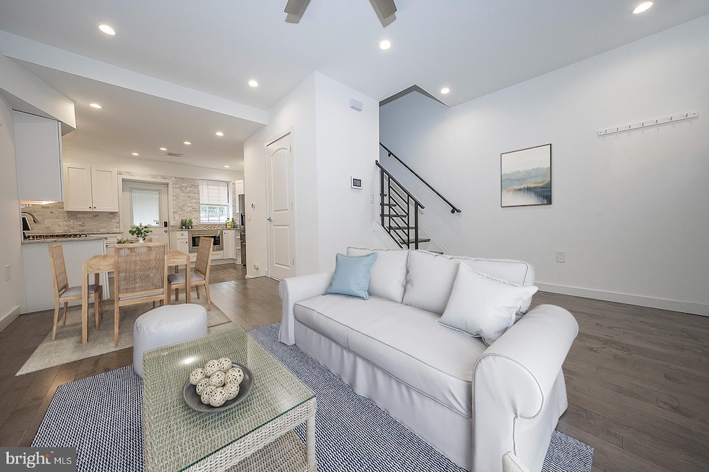 living room featuring ceiling fan and dark hardwood / wood-style floors