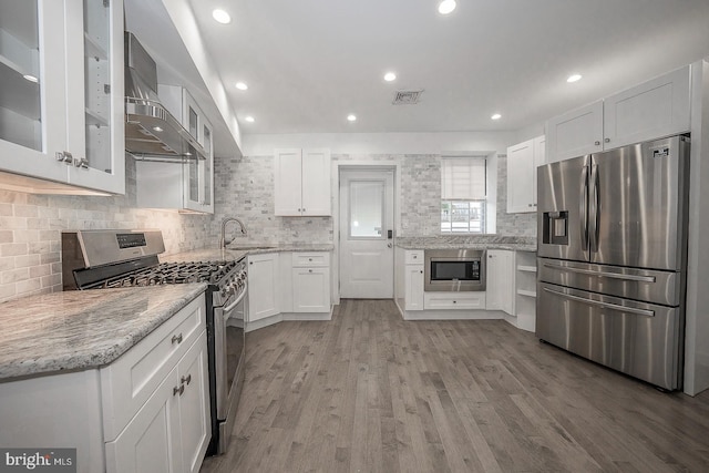 kitchen featuring sink, white cabinetry, light hardwood / wood-style flooring, light stone countertops, and appliances with stainless steel finishes