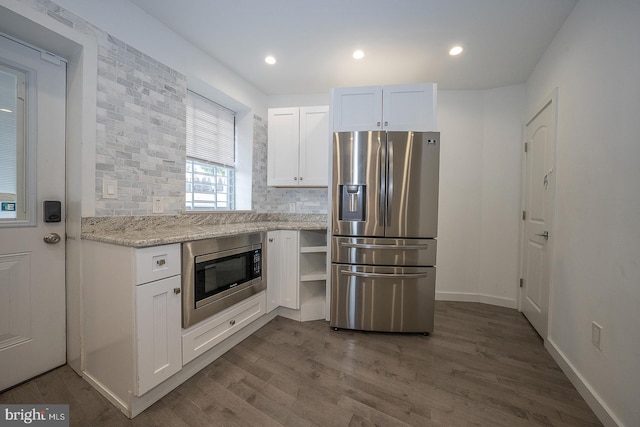 kitchen featuring appliances with stainless steel finishes, light stone countertops, dark wood-type flooring, decorative backsplash, and white cabinets