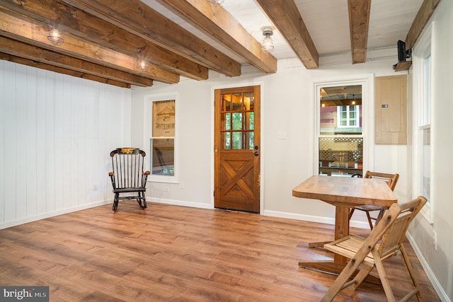 living area with a wealth of natural light, beam ceiling, light hardwood / wood-style flooring, and electric panel