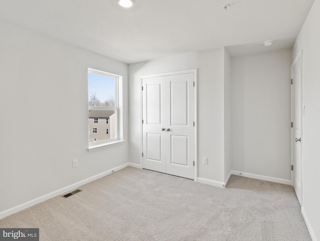 unfurnished bedroom with light carpet and a closet