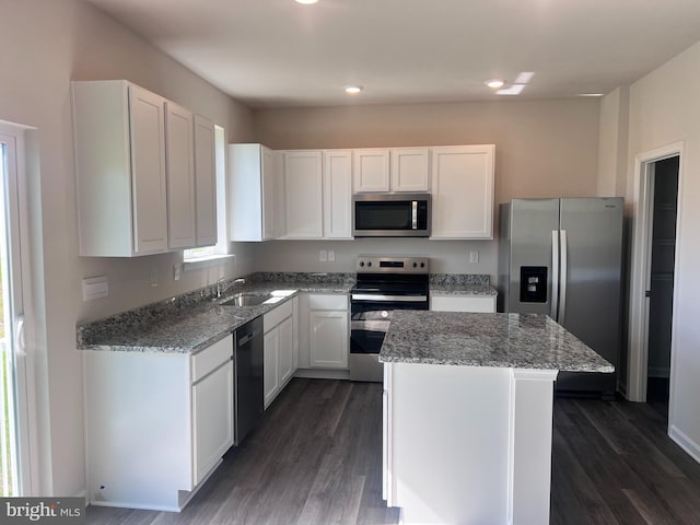 kitchen featuring a kitchen island, sink, white cabinetry, light stone countertops, and appliances with stainless steel finishes