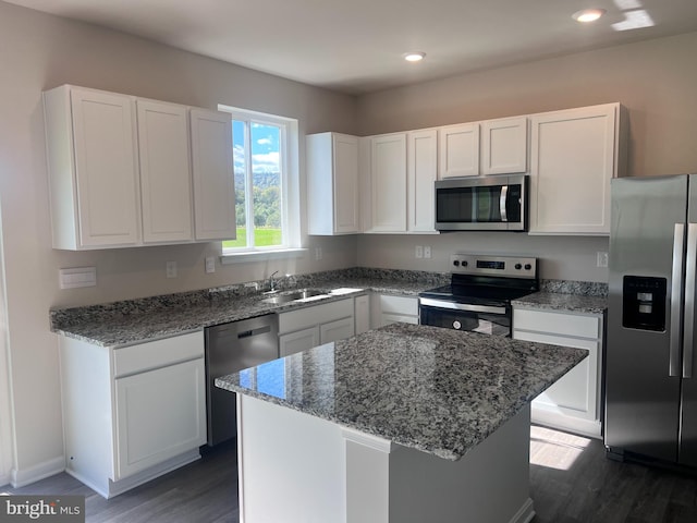 kitchen featuring white cabinetry, appliances with stainless steel finishes, a center island, and stone counters