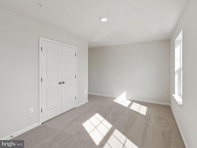 unfurnished bedroom with light carpet and a closet