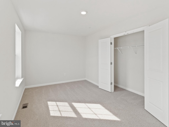 unfurnished bedroom featuring a closet and light colored carpet