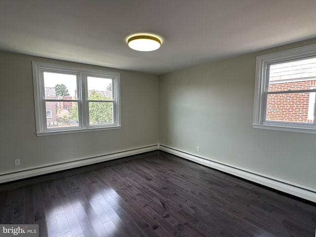 spare room with a baseboard heating unit and dark hardwood / wood-style floors