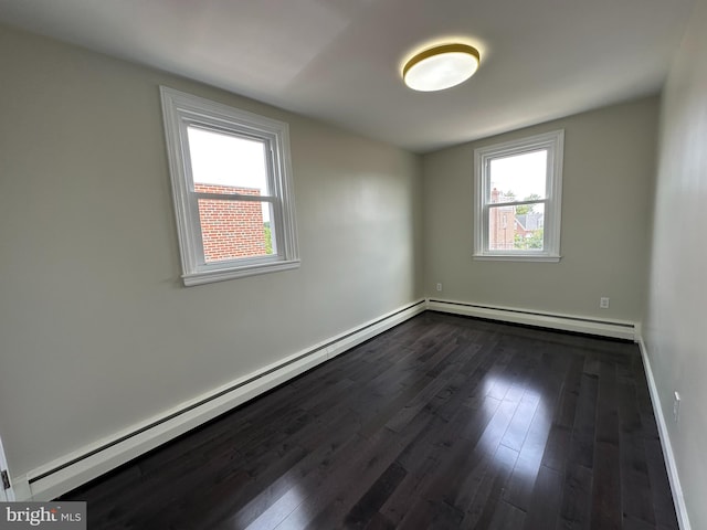 empty room featuring baseboard heating and dark hardwood / wood-style flooring