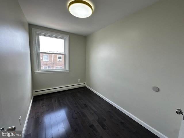 empty room with a baseboard heating unit and dark hardwood / wood-style floors