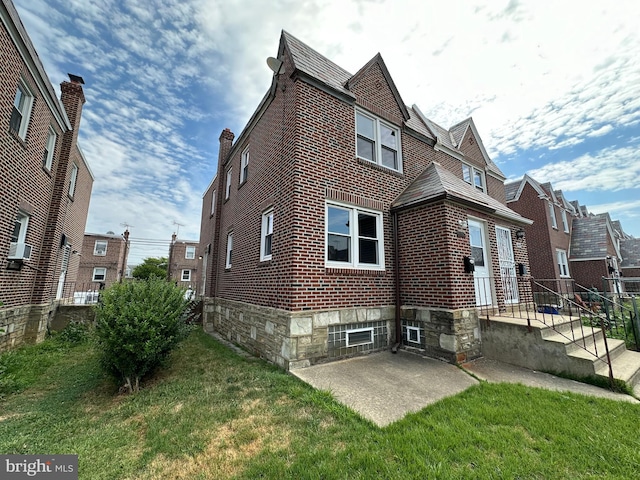 view of side of home featuring a lawn and a patio area