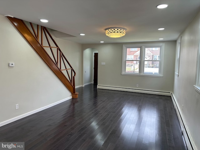 interior space with a baseboard heating unit and dark hardwood / wood-style floors