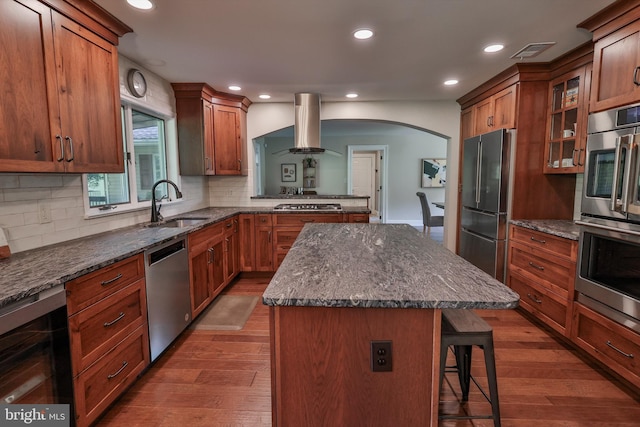 kitchen with island exhaust hood, stainless steel appliances, a center island, beverage cooler, and sink