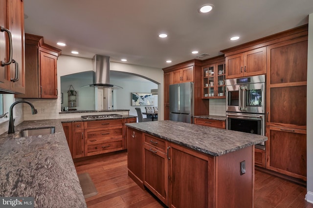 kitchen featuring tasteful backsplash, a center island, sink, island exhaust hood, and appliances with stainless steel finishes