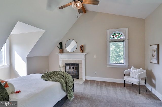 bedroom with ceiling fan, lofted ceiling, light colored carpet, and a tile fireplace